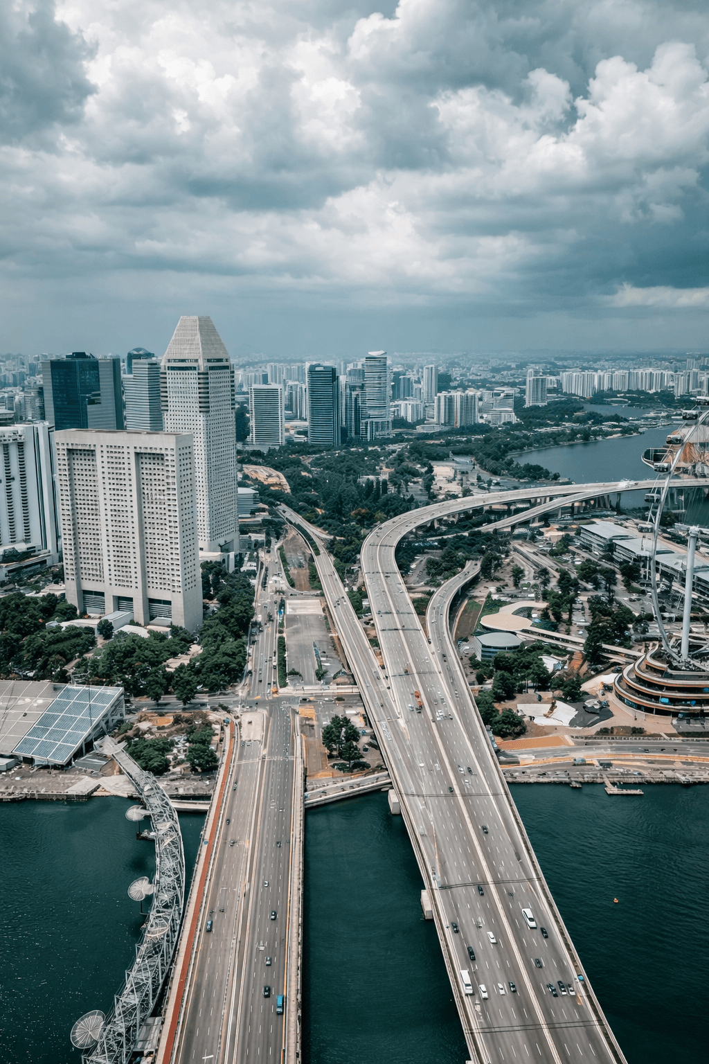 Aerial view of Singapore skyline featuring major highways, modern skyscrapers, and the Singapore Flyer near Marina Bay