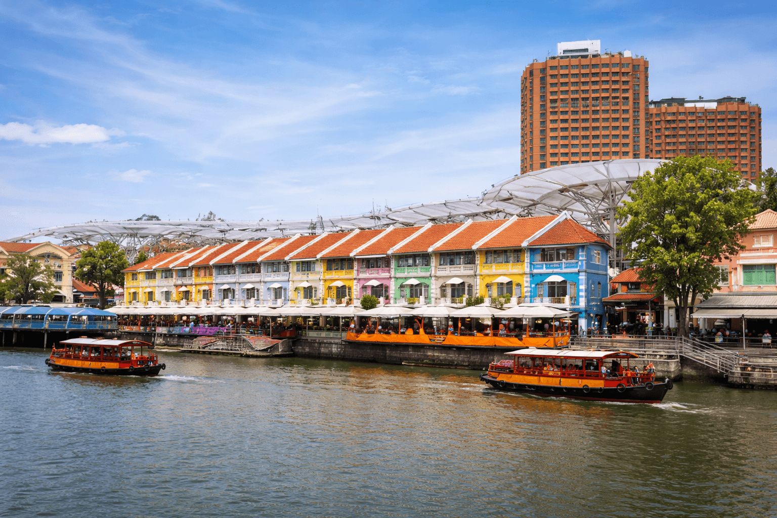 Colorful Clarke Quay riverside in Singapore with traditional bumboats cruising along the Singapore River.